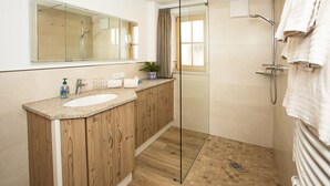 A modern bathroom with a wooden vanity, a glass shower enclosure, and a large mirror. - (4) Ferienwohnung für 1-4 Personen (63 qm, OG) (Bernau am Chiemsee)