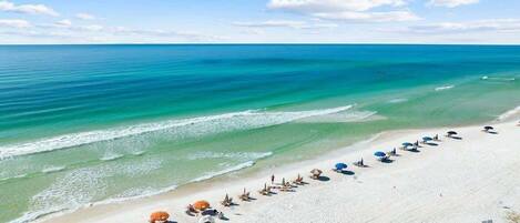 A beach with umbrellas and lounge chairs arranged in rows.