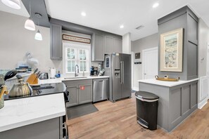 A modern kitchen with grey cabinetry, stainless steel appliances, and pendant lighting. - 2 Complimentary Beach Bikes!  Flirty Flamingo - Pet Friendly, Pool & Beach Access! (Seacrest)