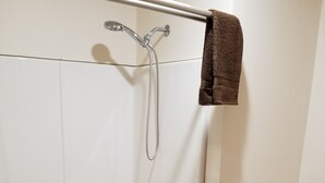 Een badkamer met een bad, toilet en een hygiëneschuimer.