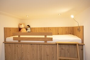 Cozy single-occupancy room with a wooden bunk bed, headboard, and bedside table.