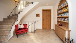 Una escalera con un sofá rojo, una puerta de madera y una estantería llena de libros.