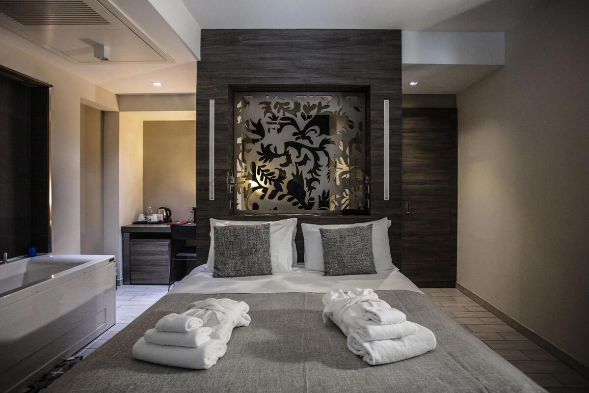 A modern hotel room with a large bed, a built-in desk, and a separate bathroom area.
