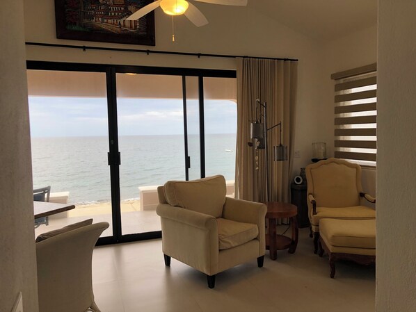 Una habitación con vista al mar, un ventilador de techo y dos sillas.