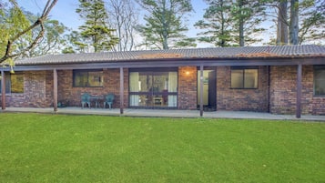 A two-story house with a covered patio, brick exterior, and a well-maintained lawn.