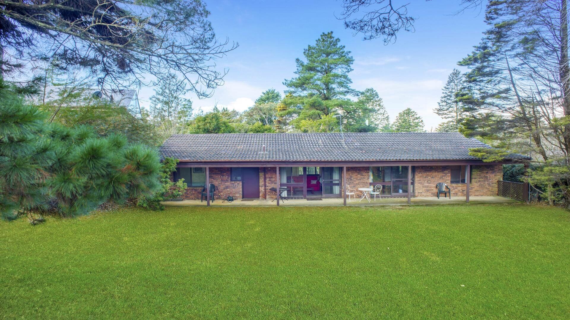 A two-story house with a covered patio area, a brick exterior, and a lawn in front.