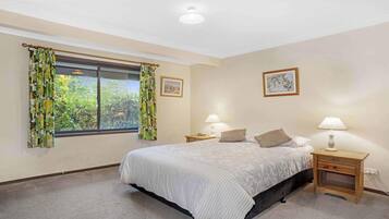 A bedroom with a bed, two bedside tables, a window with curtains, and a picture on the wall.
