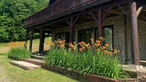 Un chalet rustique avec une façade en pierre, un balcon en bois et un jardin fleuri à l’avant.