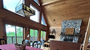 L’intérieur d’un chalet en bois comprend une table à manger, des chaises, un canapé et une cheminée en pierre.