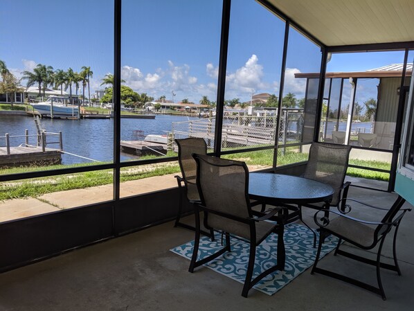 A covered outdoor seating area with a view of a marina and water. - Relax in your chair on the floating dock as the tide rolls in & catch a few fish (Hudson)