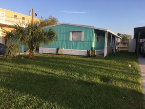 A single-story house with a green exterior and a white porch. There is a palm tree in the front yard. - Relax in your chair on the floating dock as the tide rolls in & catch a few fish (Hudson)