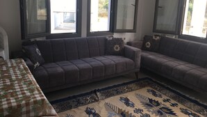 Uma sala de estar com um sofá, uma mesa com toalha quadriculada e um tapete estampado.