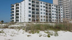 A multi-story hotel with balconies, located near a sandy beach with sparse vegetation. - Island Sunrise, sleeps 6, 2 bed / 2 bath, GULF VIEW-beach side (Gulf Shores)
