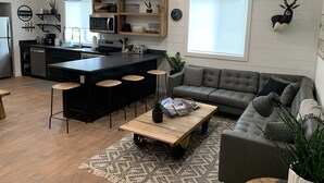 Une cuisine moderne avec un îlot central, un canapé gris et une table basse.