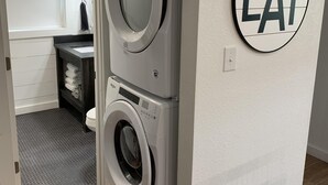 Une buanderie avec des machines à laver superposées et un panneau sur le mur indiquant « MANGER ».
