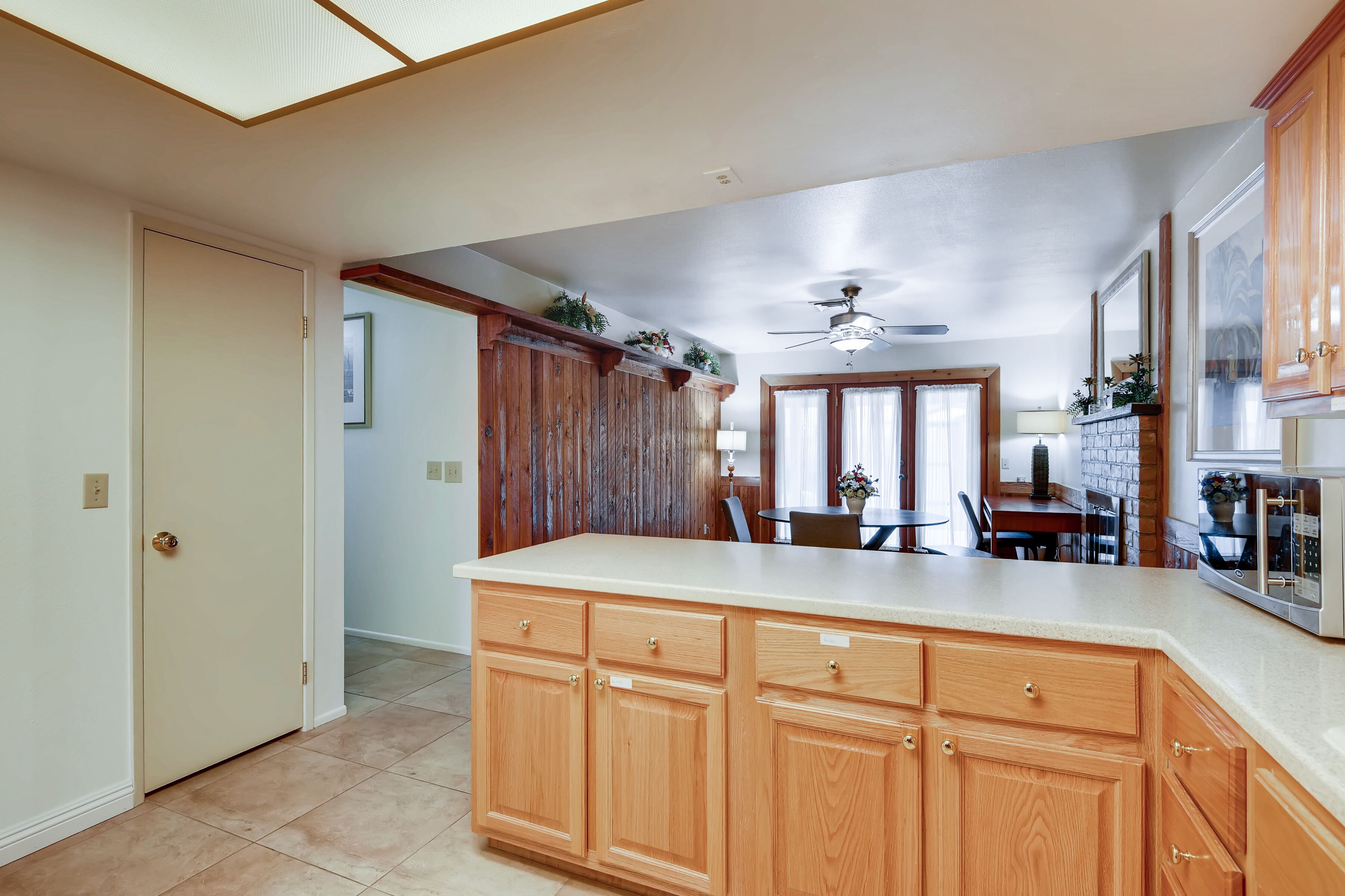 A kitchen with wooden cabinets, a large island, and a dining area with a table and chairs.