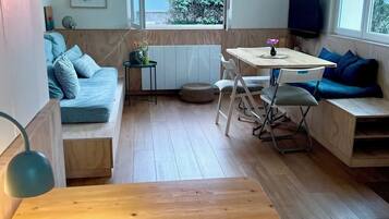 Un espace de vie moderne avec un plancher en bois, une table à manger, un canapé et un téléviseur.