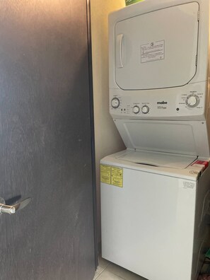 A compact, white, front-loading washing machine with multiple control knobs and a front panel with a label.
