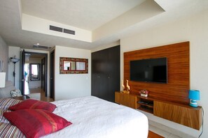Une chambre avec un grand lit, un téléviseur fixé sur un panneau en bois et une armoire.