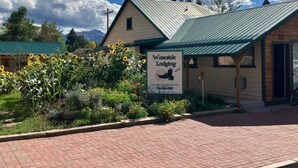 A building with a green roof and a sign for Wilderness Lodging. - Ravens Hideaway Cottage on Main, King, KItchen, Living Rm, w/d &  Patio w/Grill (Westcliffe)