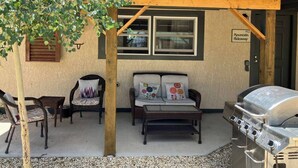 An outdoor seating area with wicker chairs and a sofa, a barbecue grill, and a tree. - Ravens Hideaway Cottage on Main, King, KItchen, Living Rm, w/d &  Patio w/Grill (Westcliffe)
