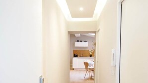 Un pasillo moderno con una cocina al fondo, que incluye una mesa de comedor y sillas.