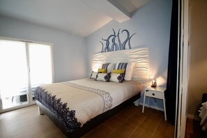 A bedroom with a bed, a nightstand, a wall art piece, and a sliding door.