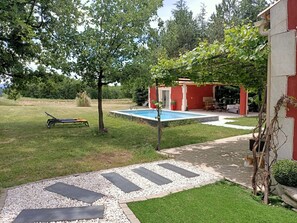 Un jardin avec une piscine, une pelouse et un espace patio.