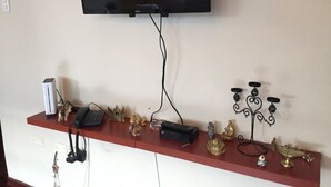 A room with a flat-screen TV mounted on the wall, a wooden shelf with various decorative items, a small heater, and a telephone. - "Your home in Miraflores" 4 pers (Lima)