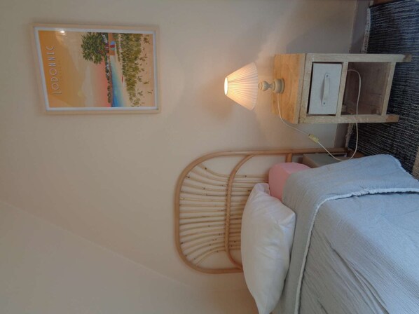 A bedroom with a bed, a bedside lamp, a small wooden cabinet, and a framed picture on the wall. - Old farmhouse with garden, close to the sea. (Plobannalec-Lesconil)