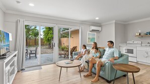 Una sala de estar moderna con un conjunto de sofá, una mesa de centro y una cocina con microondas y armarios.
