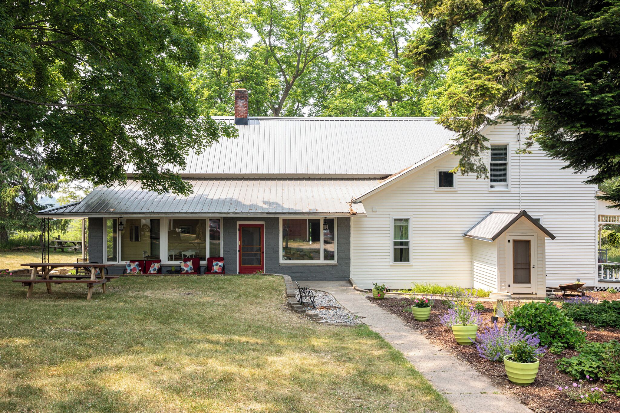 A two-story house with a porch, a small shed, and a garden with potted plants.