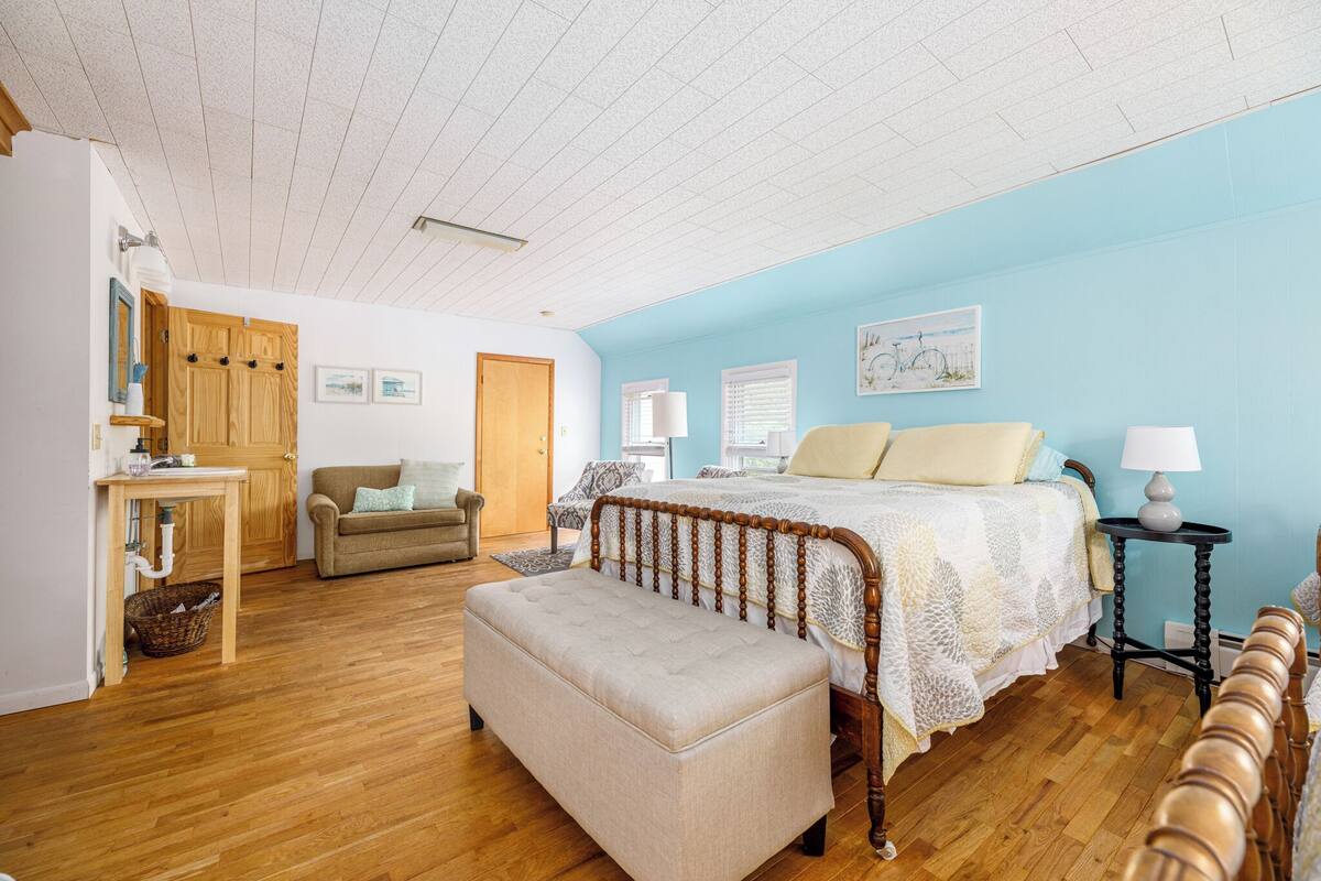 A bedroom with a wooden bed, a bench, a small table, and a chair.