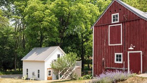 A red barn with a white door and a small white house with a porch and two chairs. - The Cottonwood Inn B&B (Empire)