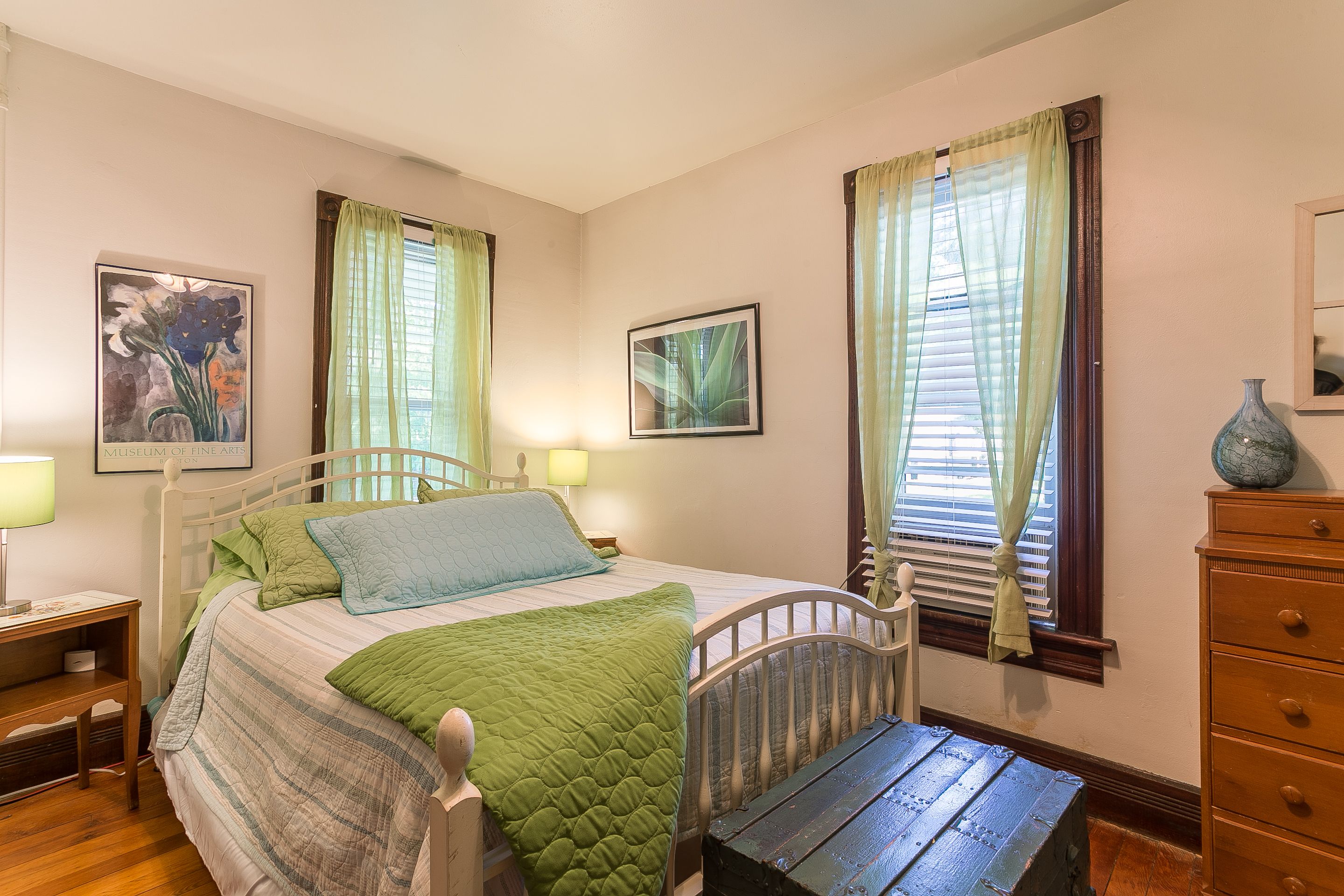 A bedroom with a bed, bedside tables, a dresser, and curtains.