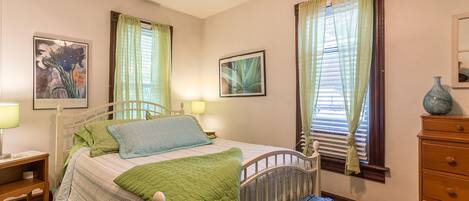 A bedroom with a bed, bedside tables, a dresser, and curtains.