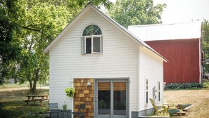 A small, single-story house with a front porch, a sliding glass door, and a small patio area with outdoor furniture. - The Cottonwood Inn B&B (Empire)