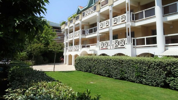 Ein mehrstöckiges Hotel mit einer symmetrischen Fassade, Balkonen und einem gepflegten Garten.
