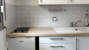 Eine kompakte Küche mit weißen Schränken, einem integrierten Geschirrspüler und einem Spülbecken mit Armatur.