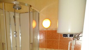 Ein Badezimmer mit Duschkabine, Toilette und Waschmaschine.