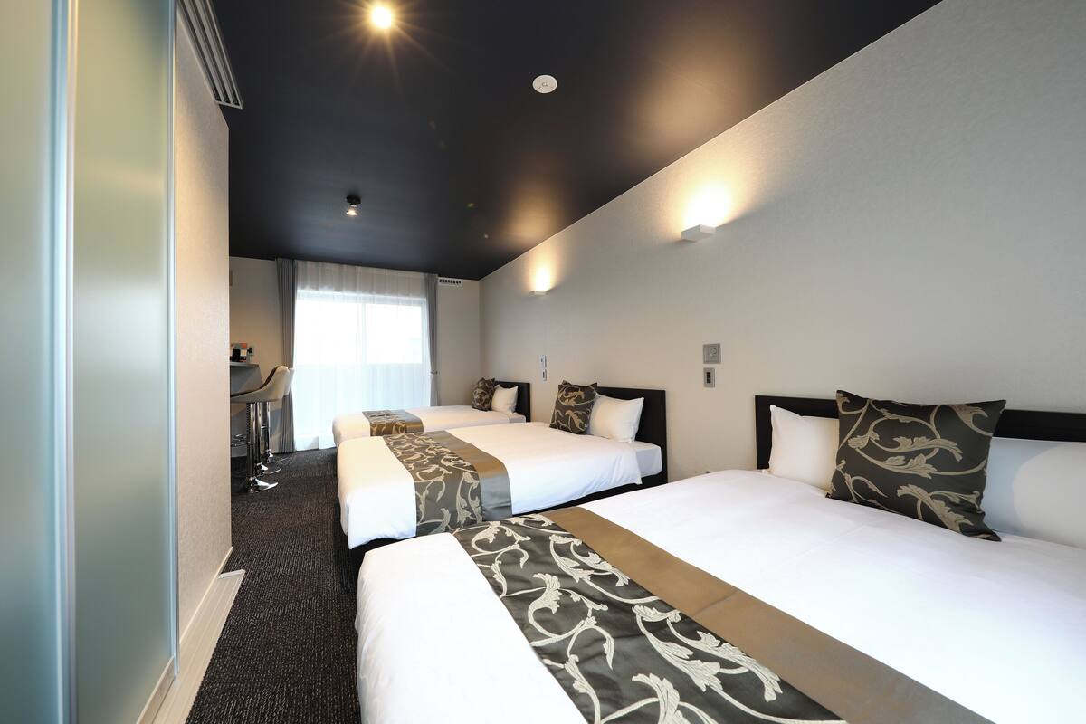 A hotel room with two beds, a desk, and a chair.