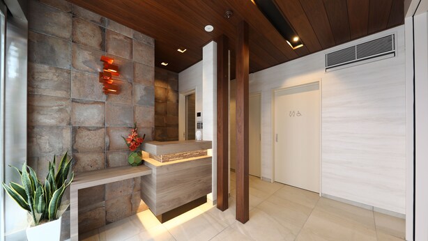 A reception area with a stone wall, wooden reception desk, and a potted plant. - GRAND BASE Hakata City (Fukuoka)