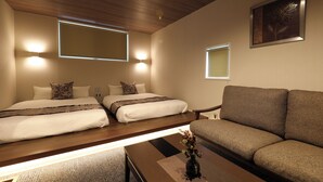 A hotel room with a bed, a sofa, a coffee table, and a wall-mounted picture. - GRAND BASE Hakata City (Fukuoka)