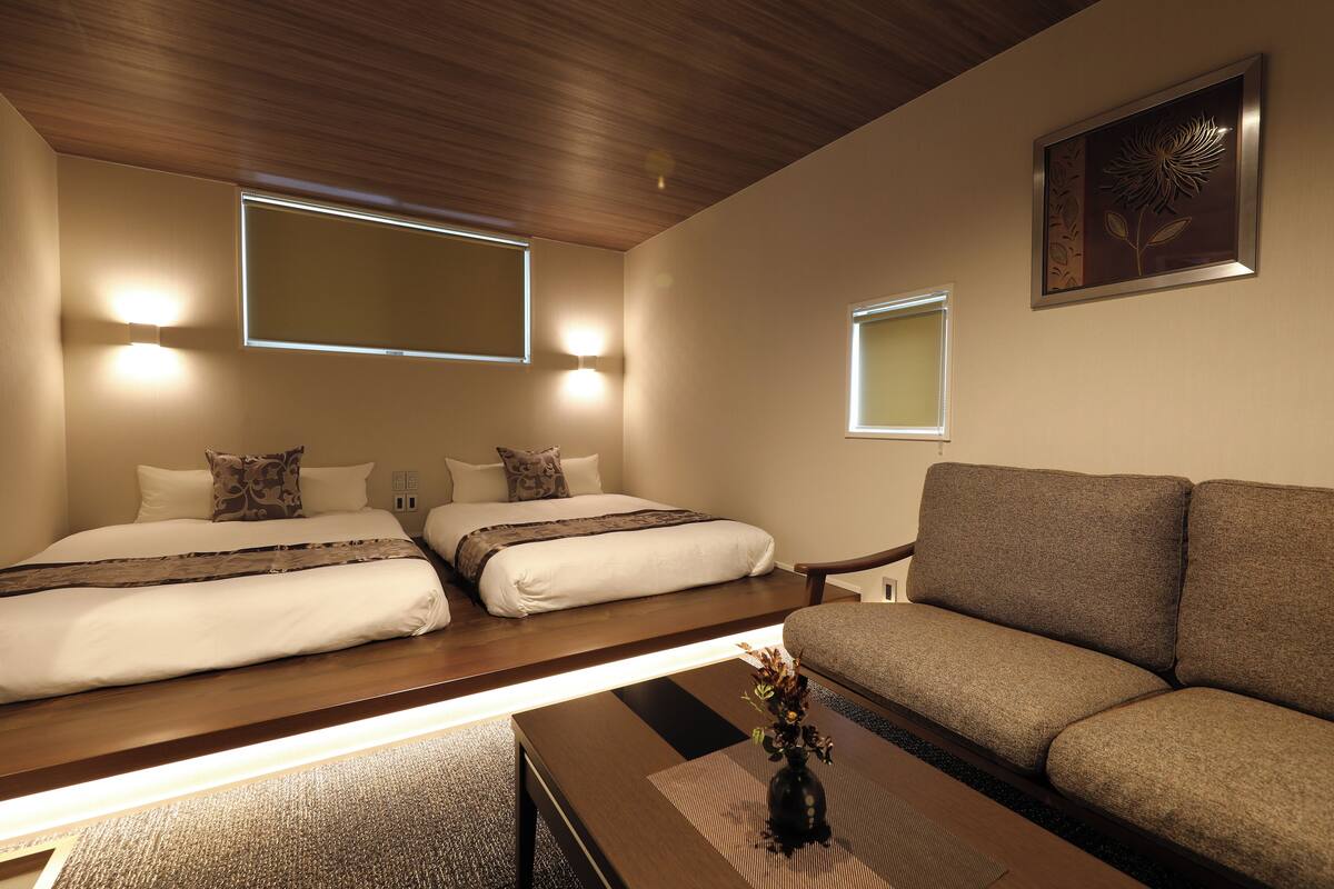 A hotel room with a bed, a sofa, a coffee table, and a wall-mounted picture.