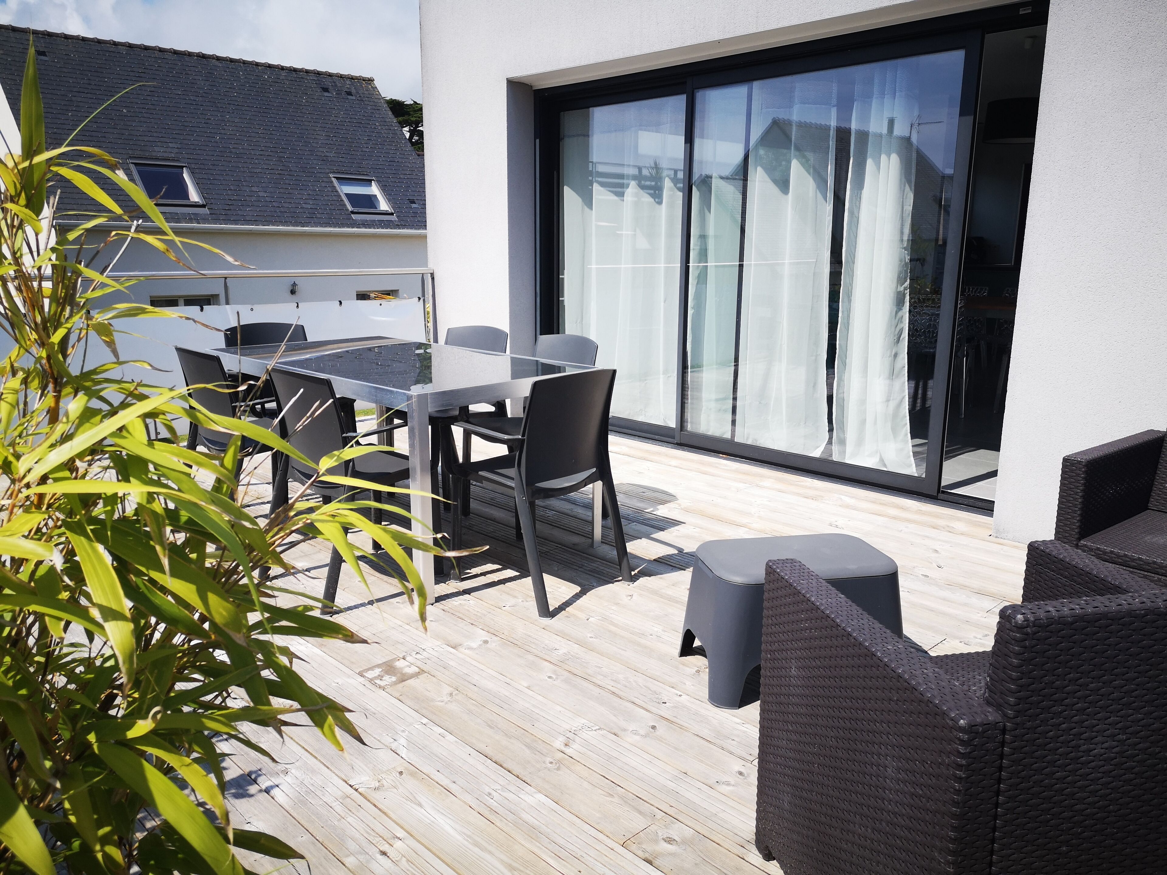 A patio with a glass table and chairs, a wicker sofa, and a sliding glass door.