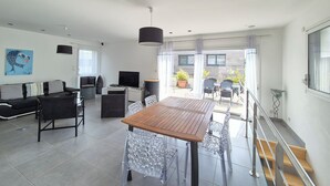 A modern living room with a sofa, TV, and dining table. - Île Tudy: House with 3 terraces  (ile tudy)