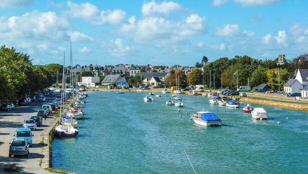 A marina with boats docked along the waterfront, surrounded by residential buildings and parked cars. - Île Tudy: House with 3 terraces  (ile tudy)