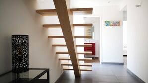 A modern interior with a wooden staircase leading to a room with a red cabinet and a painting on the wall. - Île Tudy: House with 3 terraces  (ile tudy)
