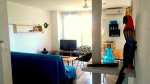 Un salon avec un téléviseur, un canapé bleu, une table basse et un perroquet.