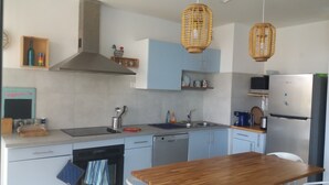 Une cuisine moderne avec une table en bois, des appareils électroménagers en acier inoxydable et des suspensions en osier.